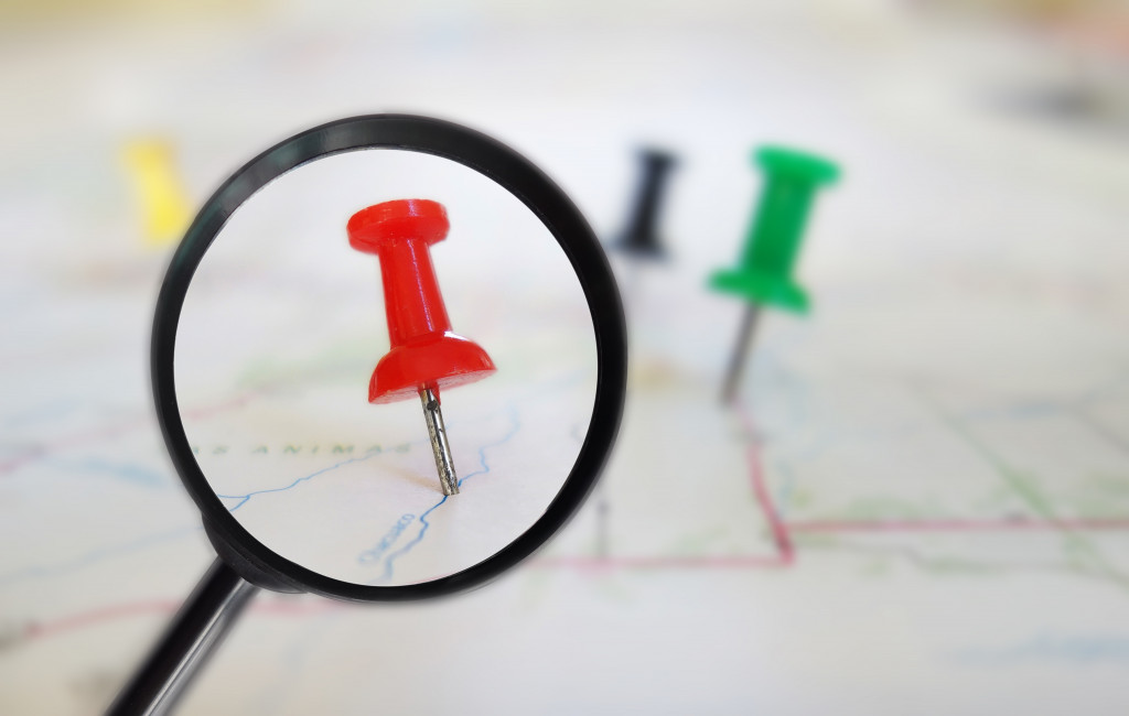 red push pin stuck in a map under a small magnifying glass